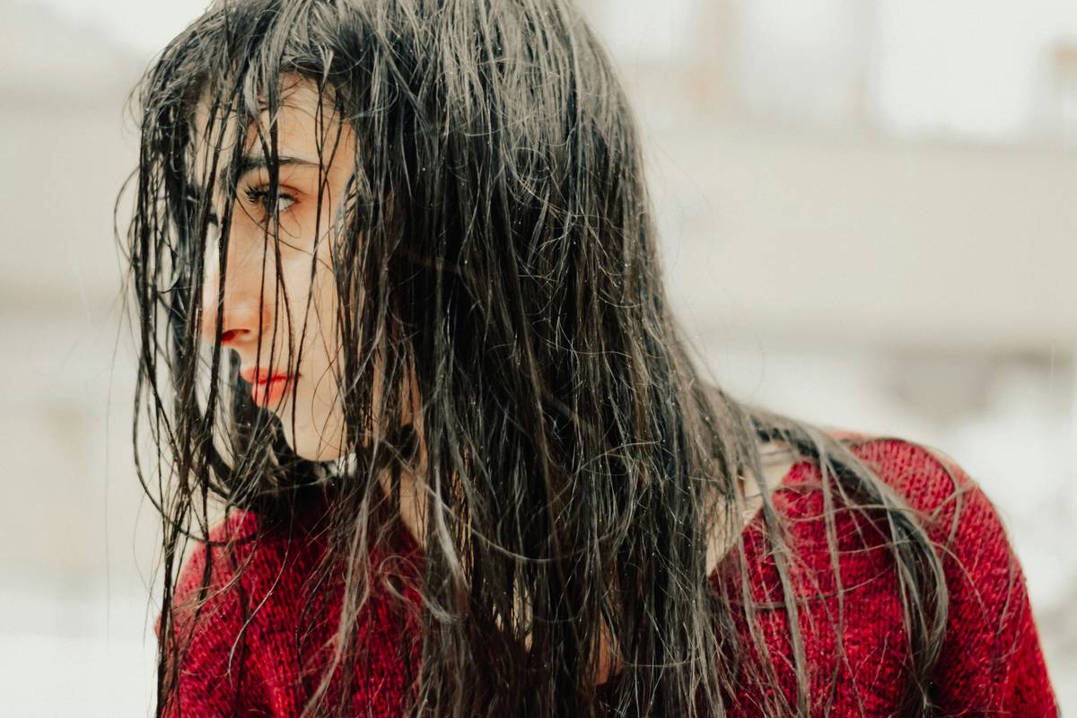 Woman applying moisture-rich conditioner to wet hair in shower